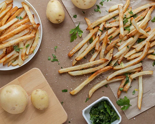 Batatas fritas em uma mesa com batatas inteiras